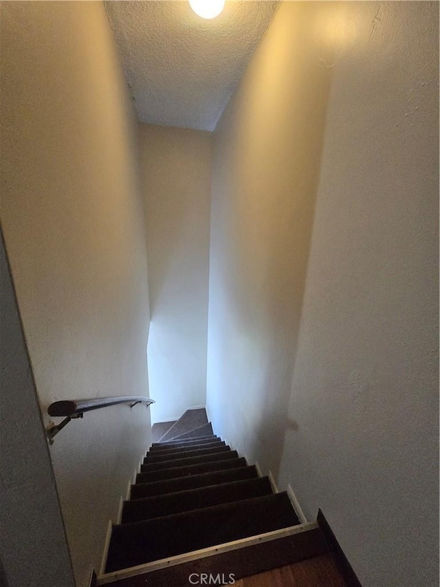 stairs with a textured ceiling