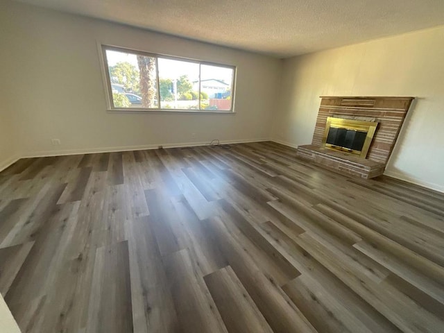 unfurnished living room with a textured ceiling, dark hardwood / wood-style flooring, and a fireplace