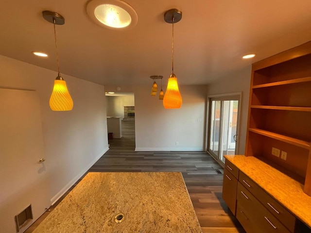 kitchen with dark hardwood / wood-style floors, light stone countertops, and hanging light fixtures