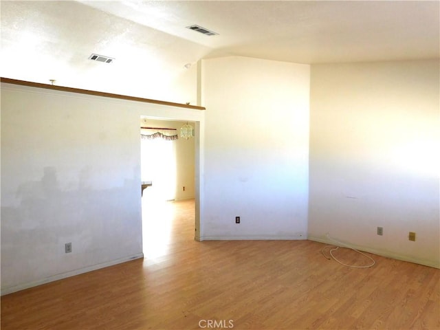 spare room with light wood-type flooring and lofted ceiling