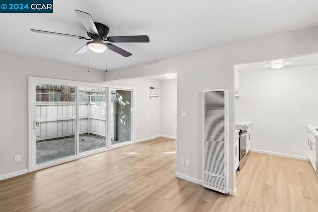 interior space with a wall mounted AC, light hardwood / wood-style floors, and ceiling fan