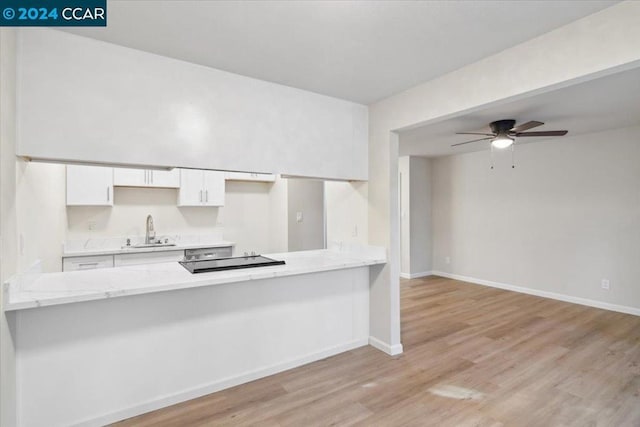 kitchen featuring white cabinets, light wood-type flooring, and kitchen peninsula