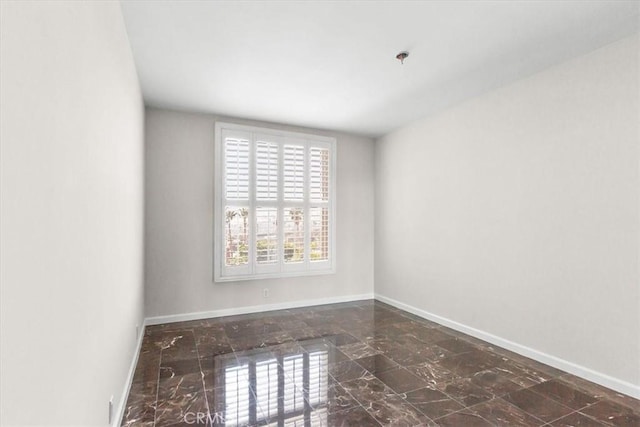 unfurnished room featuring marble finish floor and baseboards