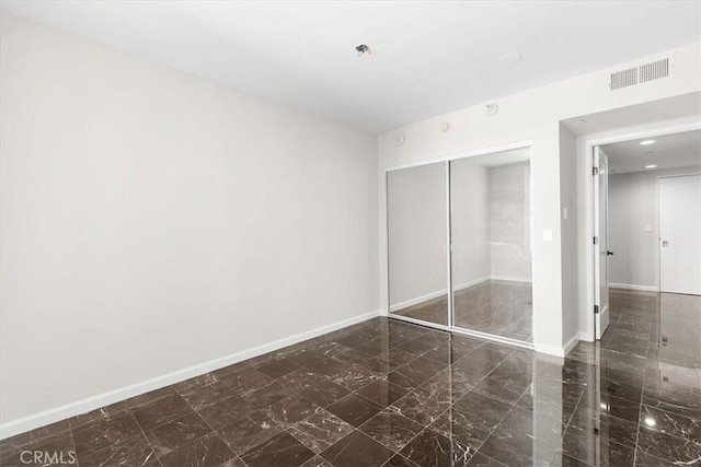 unfurnished bedroom with a closet, visible vents, marble finish floor, and baseboards