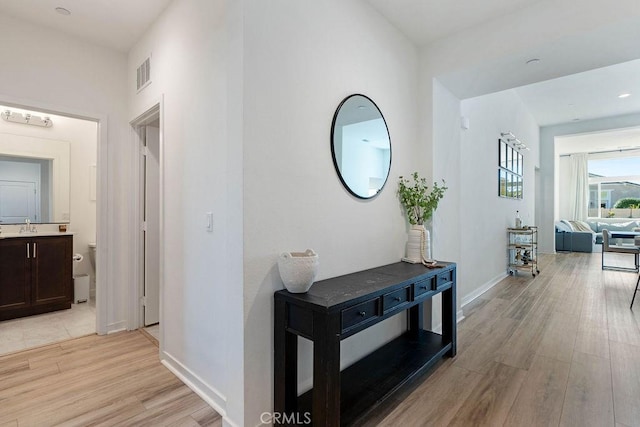 corridor with light hardwood / wood-style flooring and sink