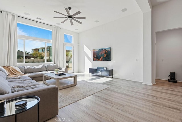 living room with a wealth of natural light, light hardwood / wood-style flooring, and ceiling fan