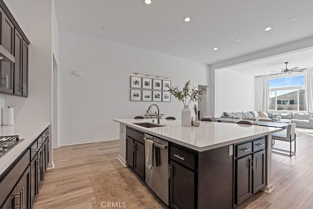 kitchen featuring appliances with stainless steel finishes, a center island with sink, light hardwood / wood-style flooring, and sink