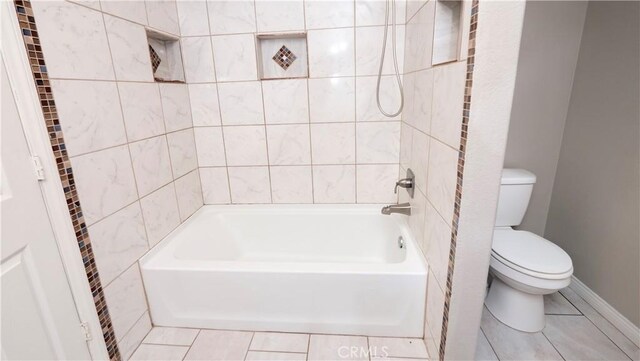 bathroom with tiled shower / bath combo, tile patterned floors, and toilet