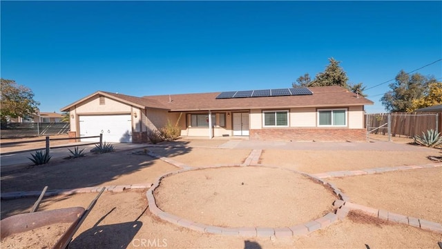 single story home with a garage and solar panels