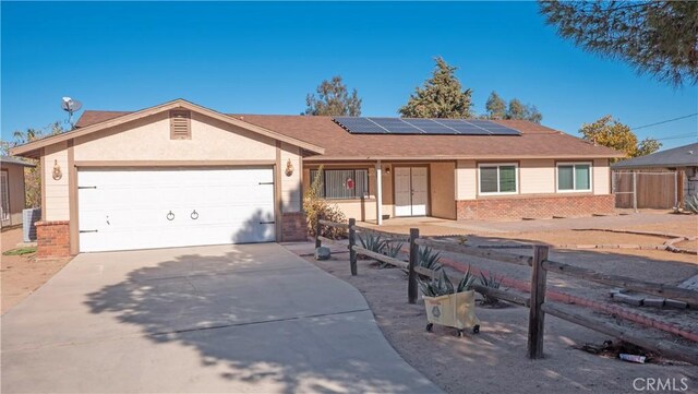 single story home featuring solar panels and a garage