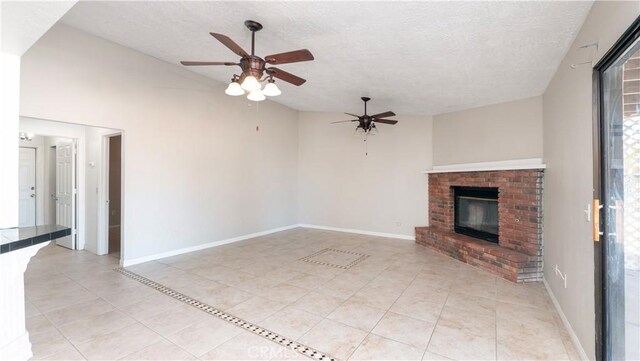 unfurnished living room featuring vaulted ceiling, a textured ceiling, light tile patterned floors, ceiling fan, and a fireplace