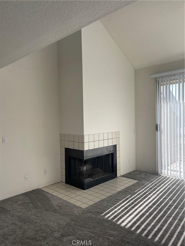 unfurnished living room with vaulted ceiling, a tile fireplace, light carpet, and a textured ceiling