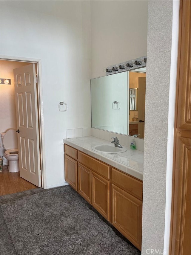 bathroom with hardwood / wood-style floors, vanity, and toilet