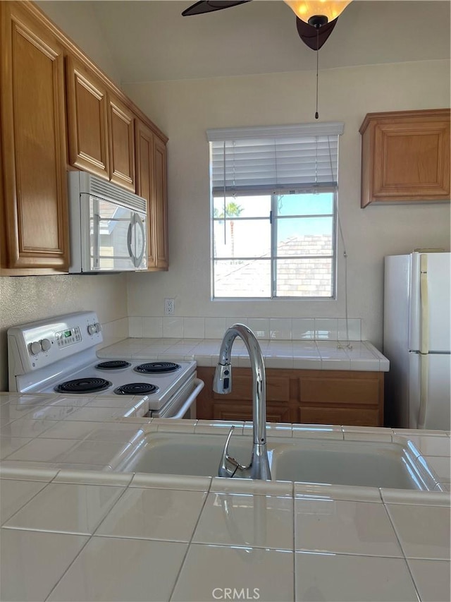 kitchen featuring white appliances, vaulted ceiling, and tile counters