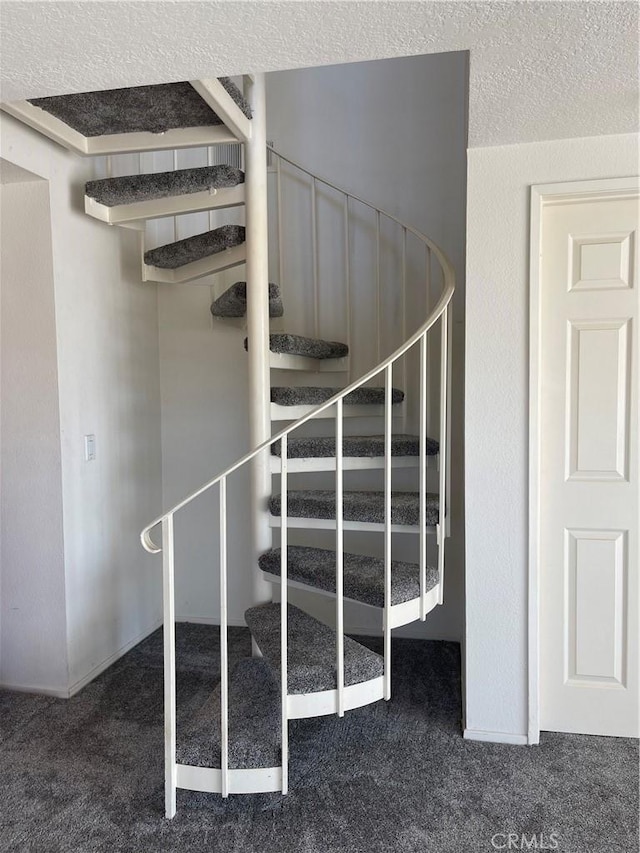 stairs with carpet floors and a textured ceiling