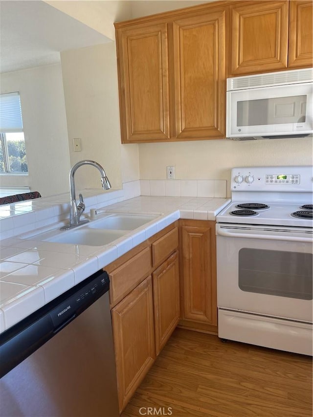 kitchen featuring tile countertops, sink, light hardwood / wood-style floors, and white appliances