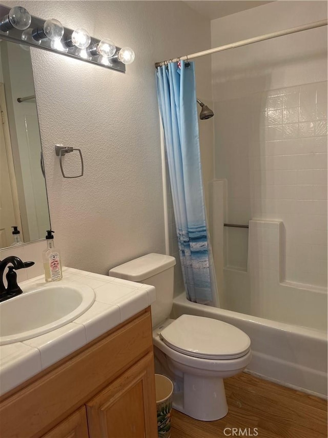 full bathroom featuring hardwood / wood-style floors, shower / bath combination with curtain, toilet, and vanity