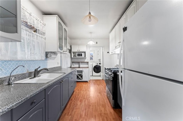 kitchen featuring pendant lighting, white appliances, white cabinets, sink, and light hardwood / wood-style flooring