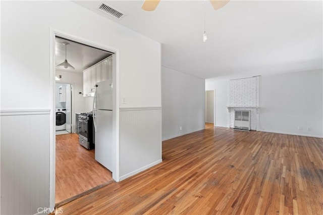 unfurnished living room with washer / clothes dryer, ceiling fan, and hardwood / wood-style flooring