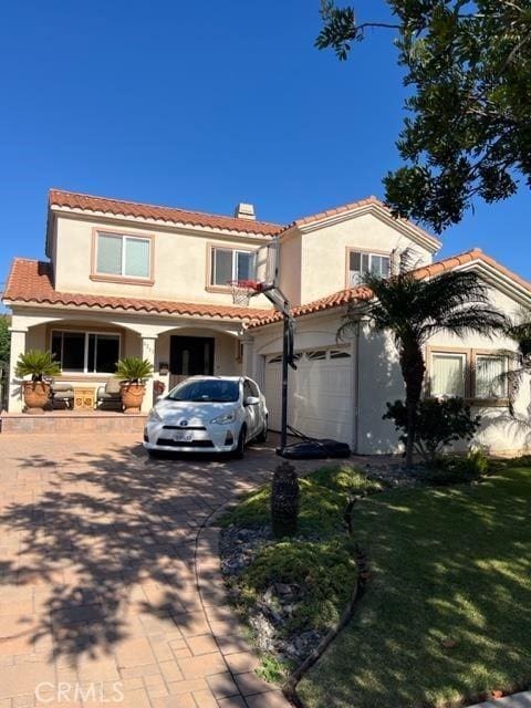 mediterranean / spanish-style home featuring a garage and a front lawn