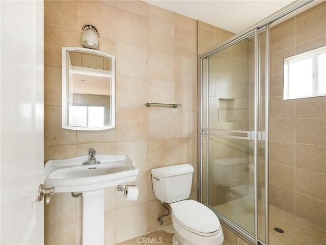 bathroom featuring tile walls, a shower with shower door, and toilet