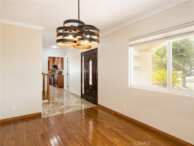 entrance foyer with ornamental molding, a notable chandelier, and light hardwood / wood-style flooring