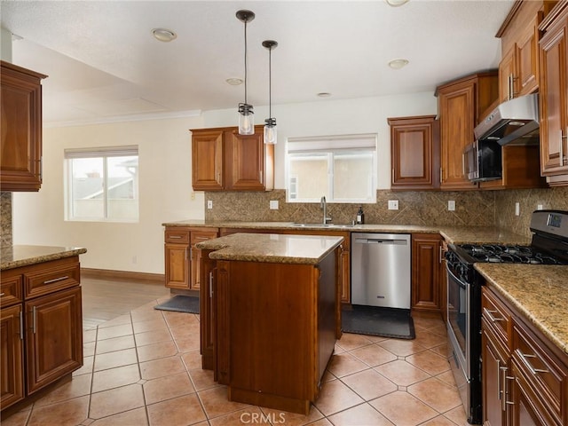 kitchen featuring a kitchen island, appliances with stainless steel finishes, pendant lighting, sink, and light stone counters