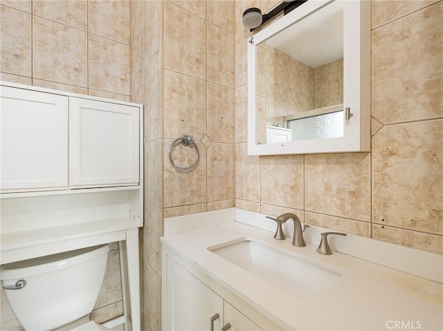 bathroom featuring vanity, toilet, tile walls, and backsplash