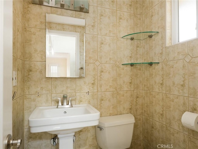 bathroom with tile walls, sink, and toilet