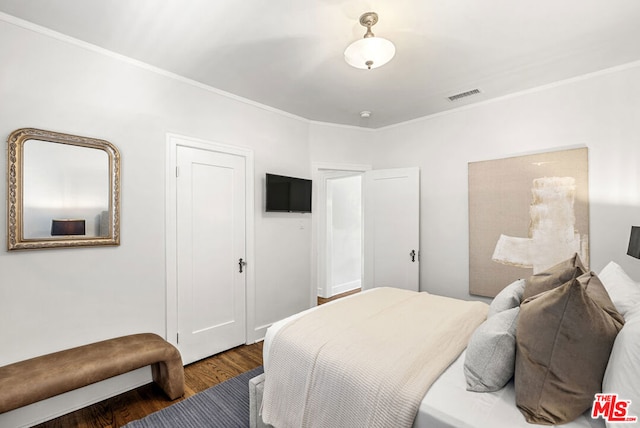 bedroom with ornamental molding and dark wood-type flooring