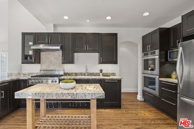 kitchen with hardwood / wood-style floors, light stone counters, sink, and stainless steel appliances