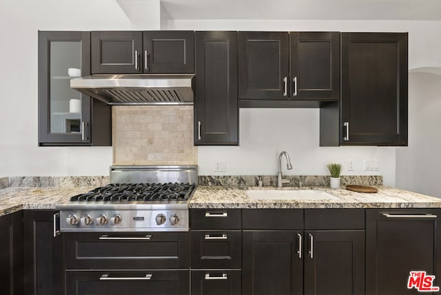 kitchen featuring light stone countertops, sink, range hood, and stainless steel gas cooktop