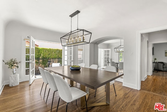 dining space featuring french doors, dark hardwood / wood-style floors, and a notable chandelier