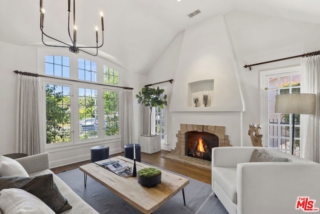 living room featuring a fireplace, dark hardwood / wood-style flooring, high vaulted ceiling, and a notable chandelier