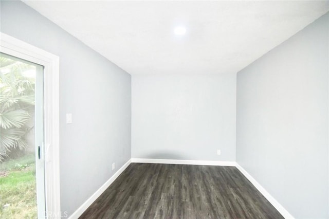 spare room featuring dark wood-type flooring and baseboards