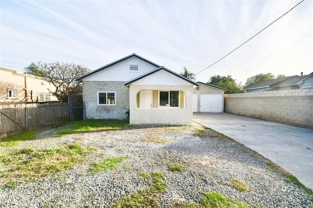 bungalow-style home featuring fence, concrete driveway, and stucco siding