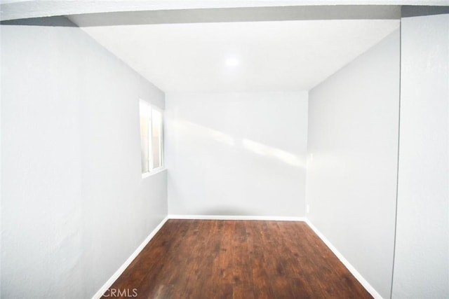 spare room with baseboards and wood finished floors