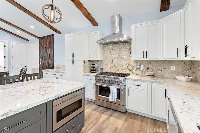 kitchen featuring white cabinets, wall chimney range hood, and appliances with stainless steel finishes