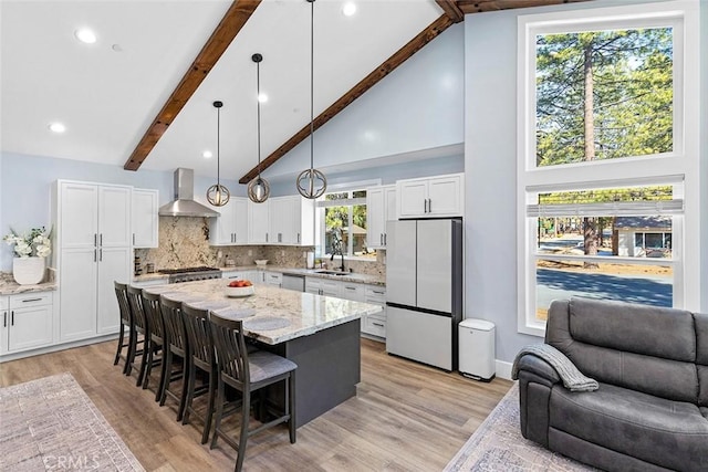 kitchen featuring pendant lighting, white fridge, white cabinetry, and wall chimney exhaust hood