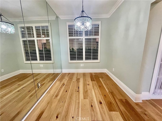 unfurnished dining area with wood-type flooring, an inviting chandelier, and crown molding