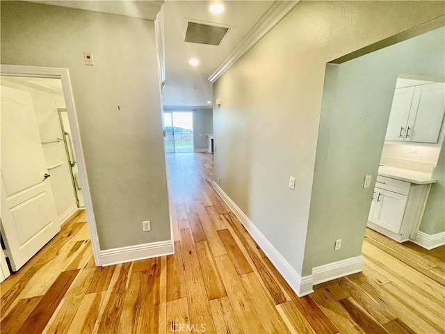 hallway with light hardwood / wood-style flooring and ornamental molding