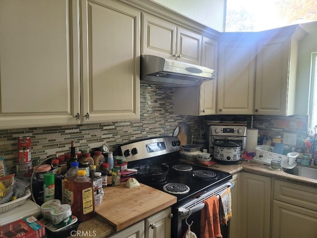 kitchen with stainless steel electric stove, decorative backsplash, and wood counters