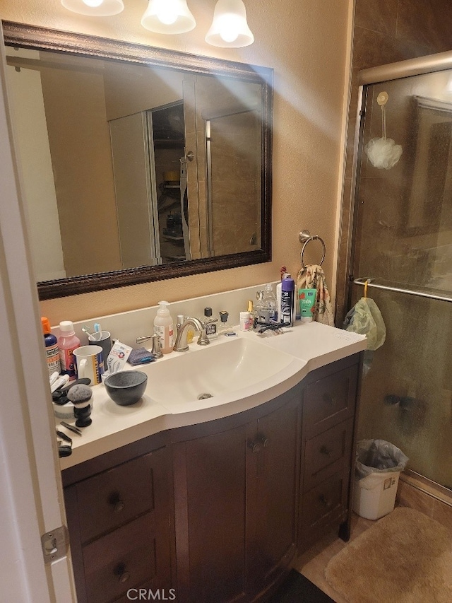 bathroom featuring a shower with shower door and vanity