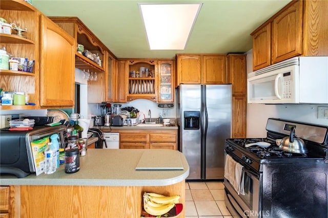 kitchen with light tile patterned flooring, appliances with stainless steel finishes, kitchen peninsula, and sink