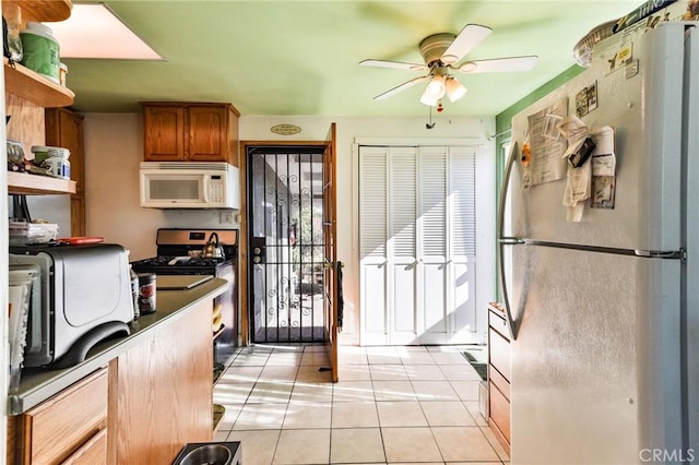 kitchen with light tile patterned floors, stainless steel appliances, and ceiling fan