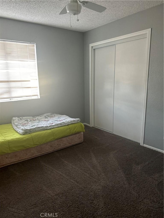 bedroom featuring ceiling fan, carpet floors, a textured ceiling, and a closet