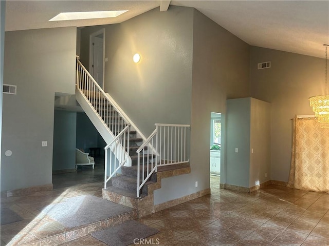 stairs with beamed ceiling, a skylight, high vaulted ceiling, and a notable chandelier