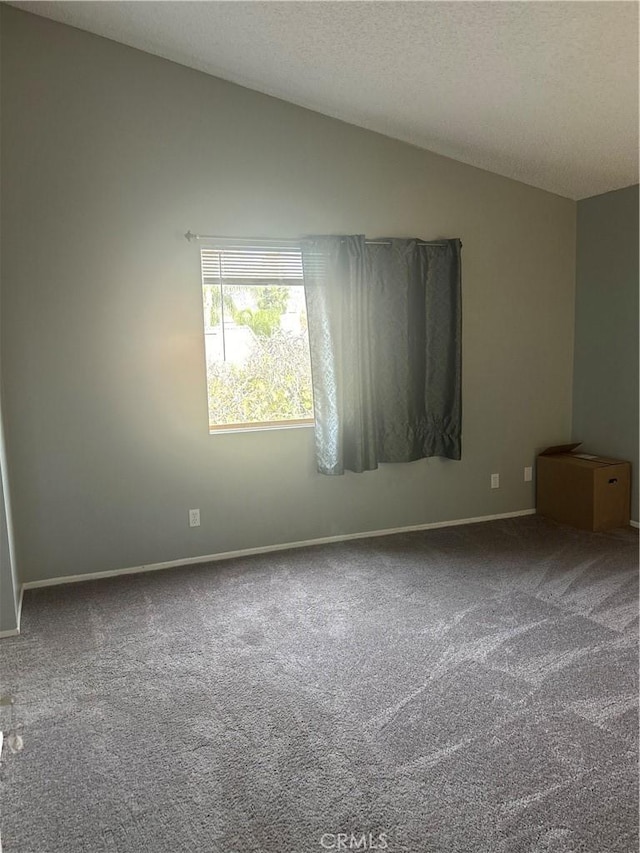 unfurnished room featuring a textured ceiling, lofted ceiling, and carpet floors