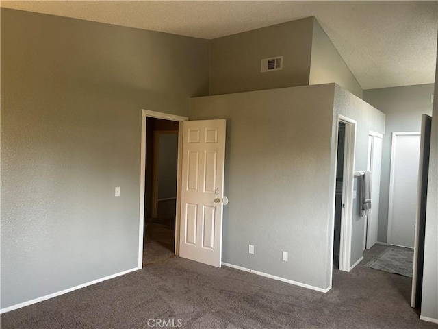 unfurnished bedroom with dark carpet and high vaulted ceiling