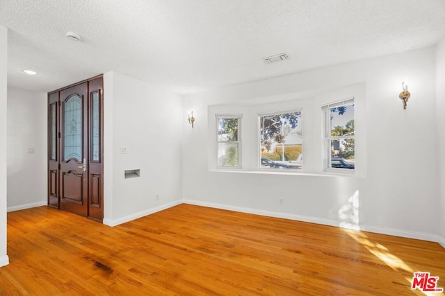 empty room with wood-type flooring and a textured ceiling